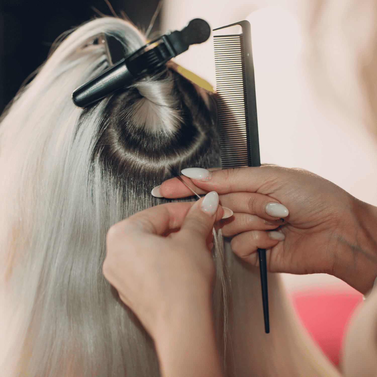 Hair stylist sections long blonde hair with a comb and clip for styling or treatment.